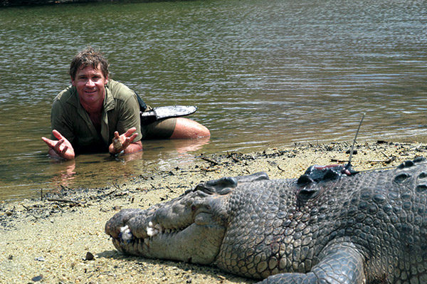 Steve Irwin laying in the water with a croc.