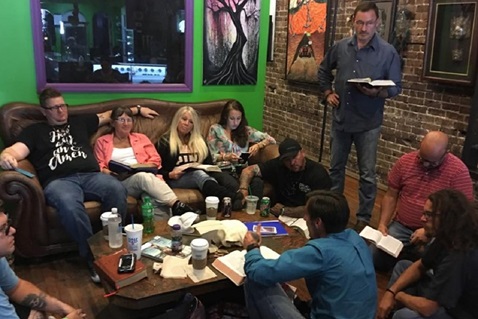 The Rev. Michael Beck (seated on the floor in a blue shirt) leads a Bible study at Tattoo Parlor Church, a Fresh Expression that has been gathering for over a decade in Ocala, Florida. Photo courtesy of Tattoo Parlor Church.