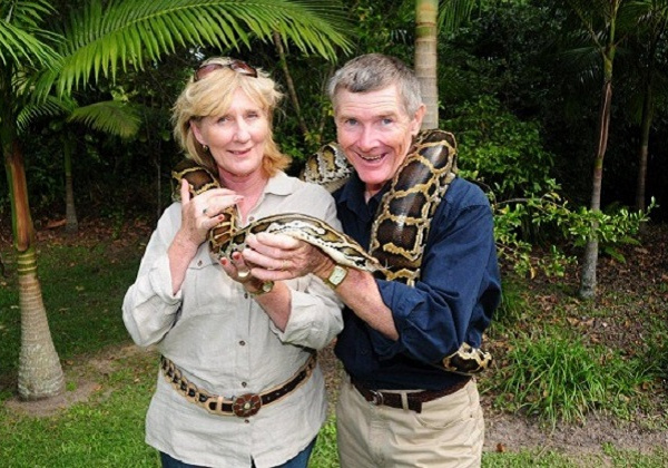 Two visitors and a snake wrapped around their shoulders.